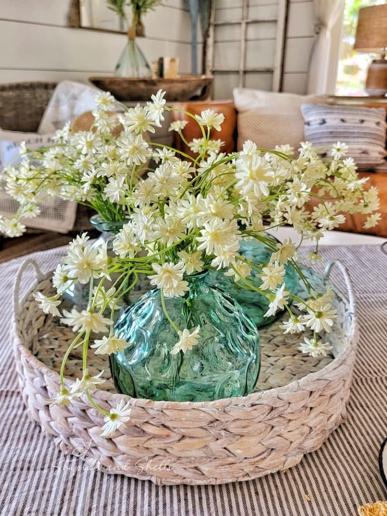 aqua colored glass jars with faux flowers inside a basket