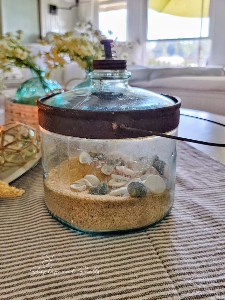 vintage glass container with sand and seashells