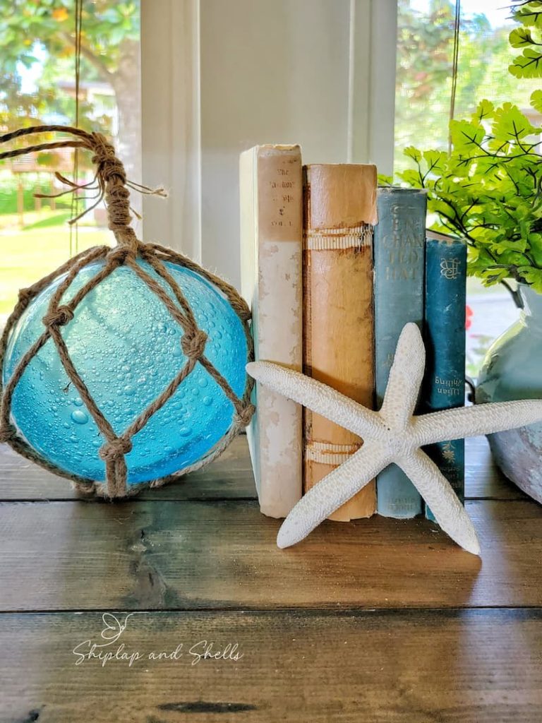 aqua glass float, blue and beige vintage books and starfish