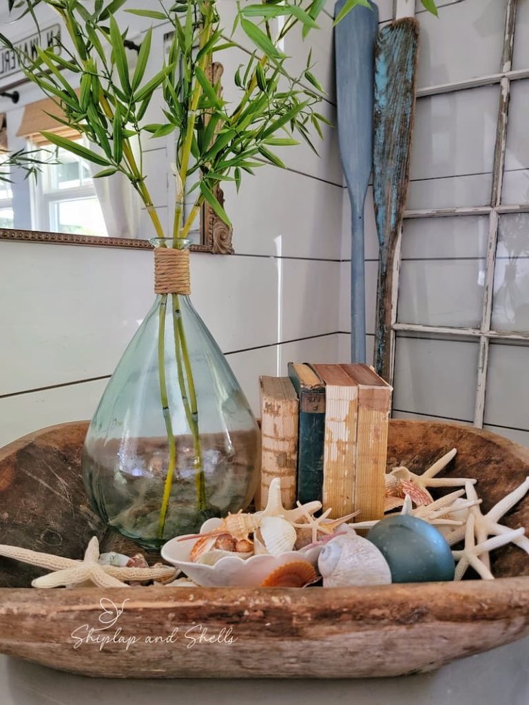wooden dough bowl with shells, vintage books and glass vase