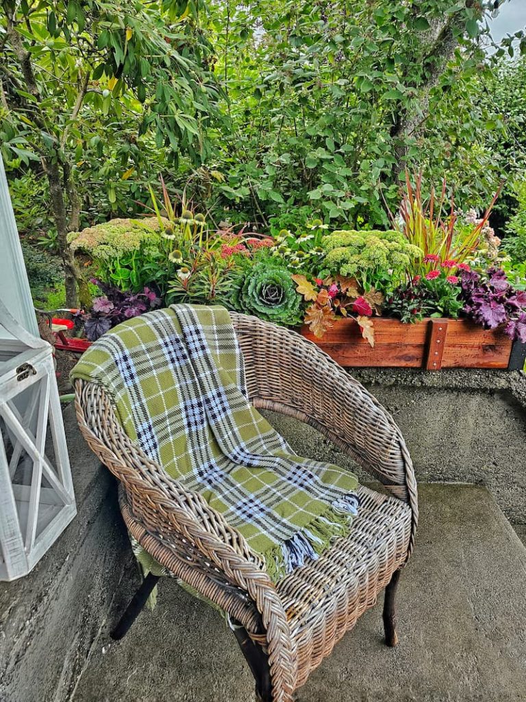 Outdoor Fall Decorating Ideas: wicker chair with green plaid throw and fall flowers