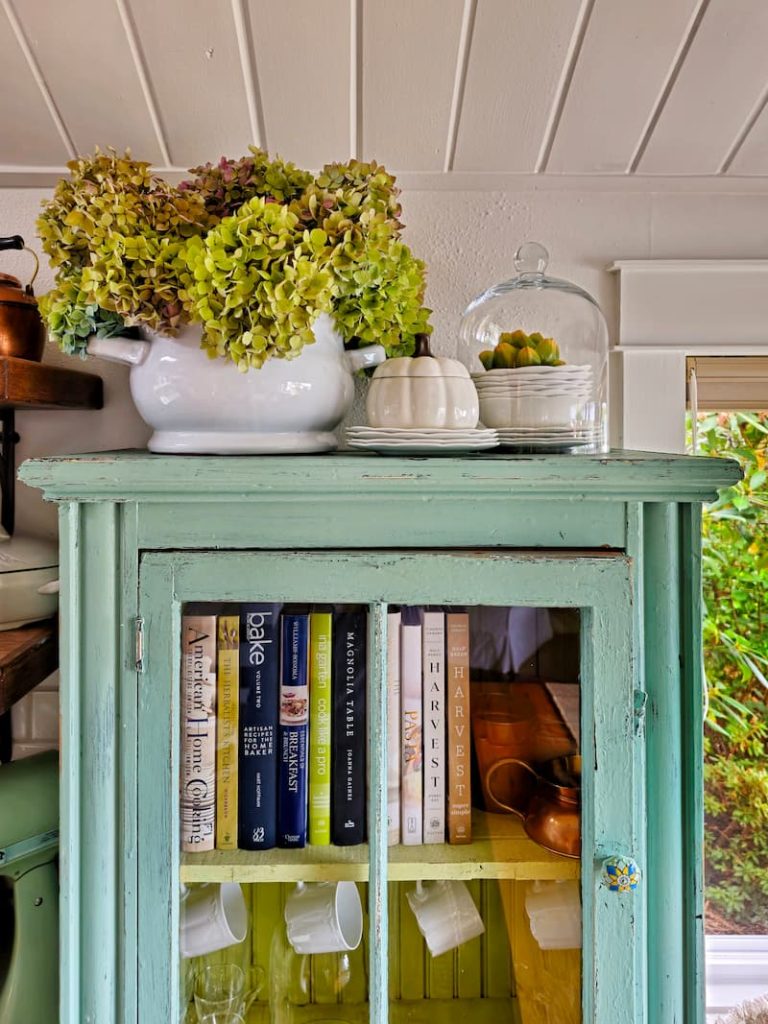 turquoise cabinet with recipe books and hydrangeas on top