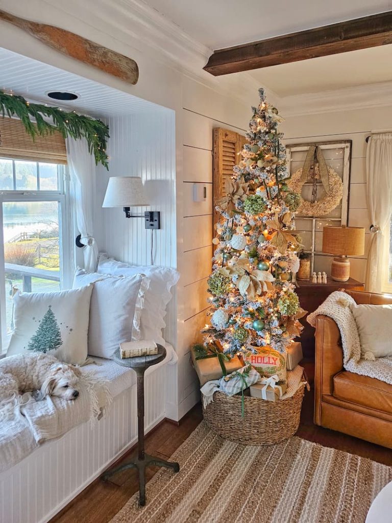 Green and white Christmas decor: Christmas tree and dog lying on the window seat