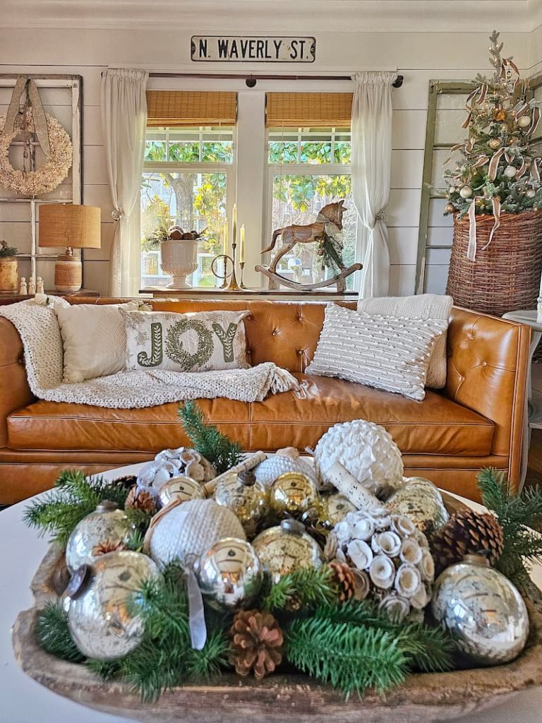 Green and white Christmas decor: ornaments in wooden dough bowl and couch with Joy pillow