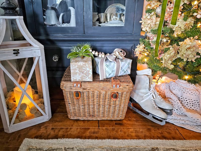 wrapped Christmas gifts on top of vintage wicker picnic basket and pair of white ice skates