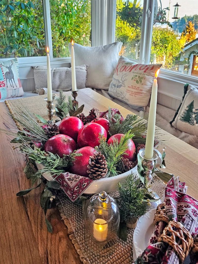 Mixing vintage and modern Christmas decor: Christmas centerpiece on table with bowl of red pomegranates and candlesticks