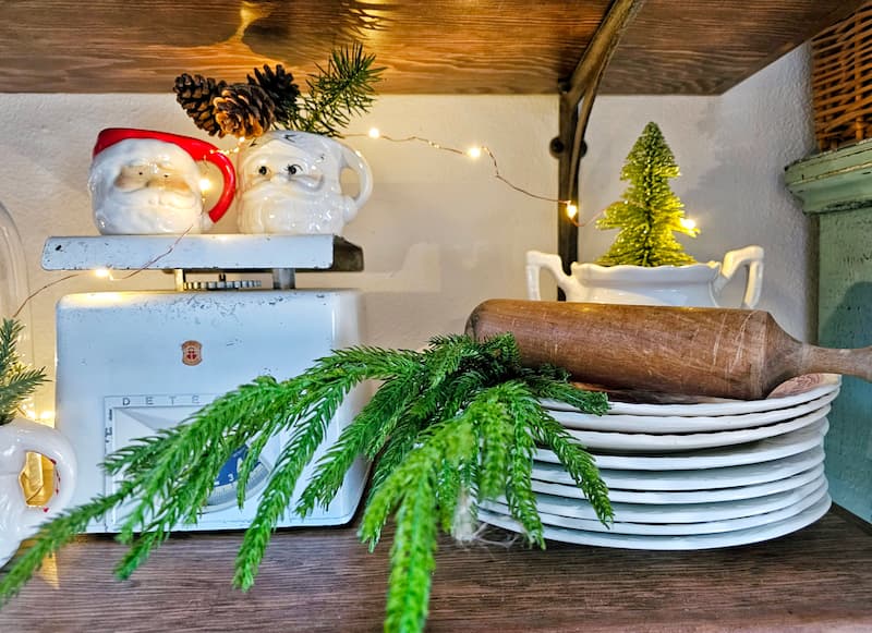 Mixing vintage and modern Christmas decor: vintage scale, Santa mugs, and dishes with greenery and wooden rolling pin