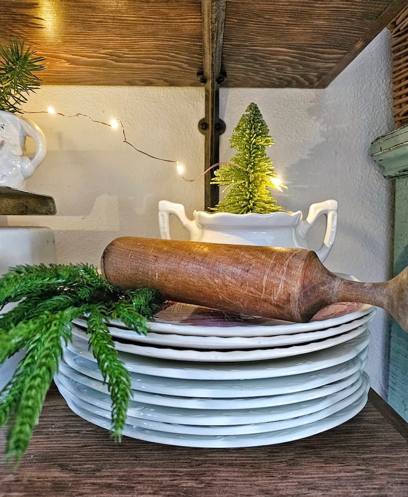Mixing vintage and modern Christmas decor: white ironstone dishware and wooden rolling pin with greenery