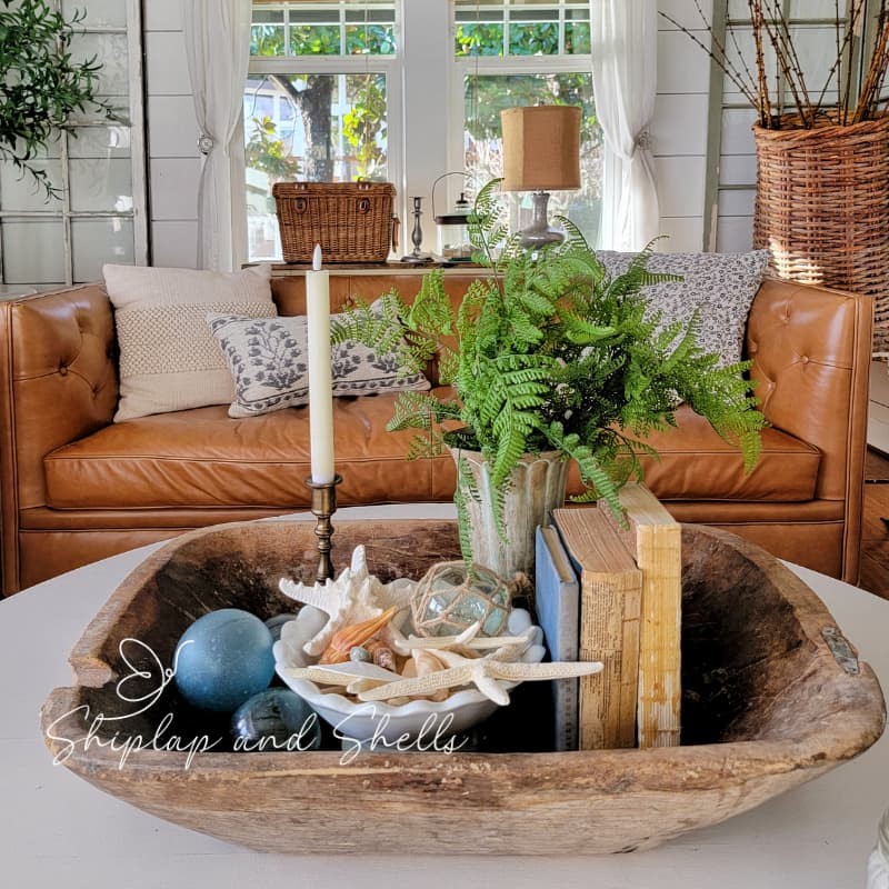 spring vintage home decor: sea shells and vintage books and candlesticks in wooden dough bowl