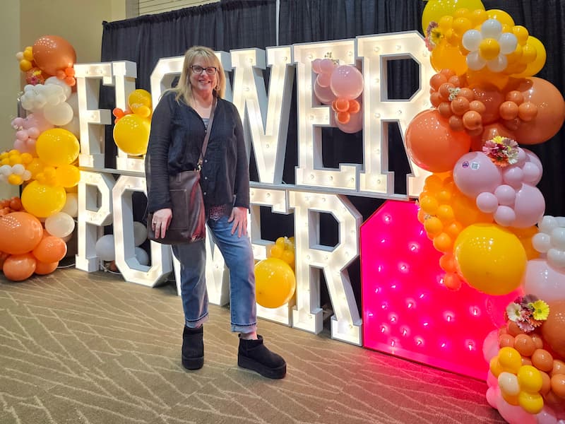 standing in front of the Flower Power sign at the Northwest Flower and Garden Festival