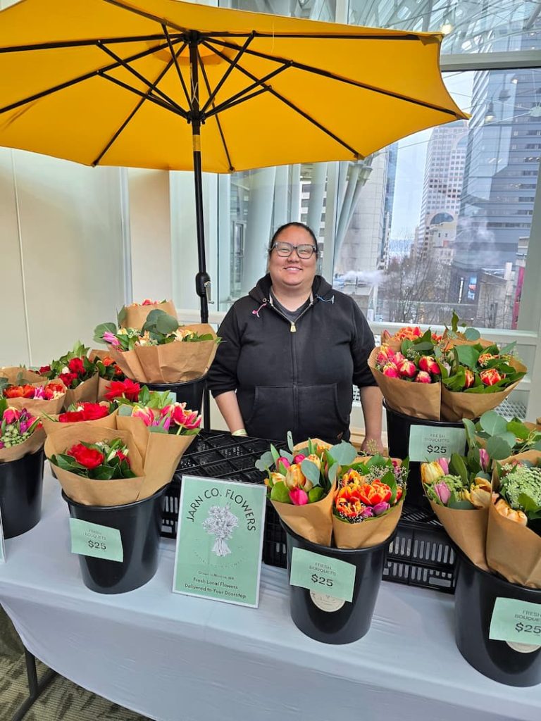 woman selling flower bouquets under yellow umbrella