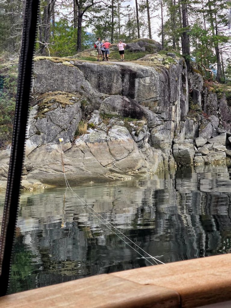 Prideaux Haven - Melanie Cove with people hiking on rock in front of our boat