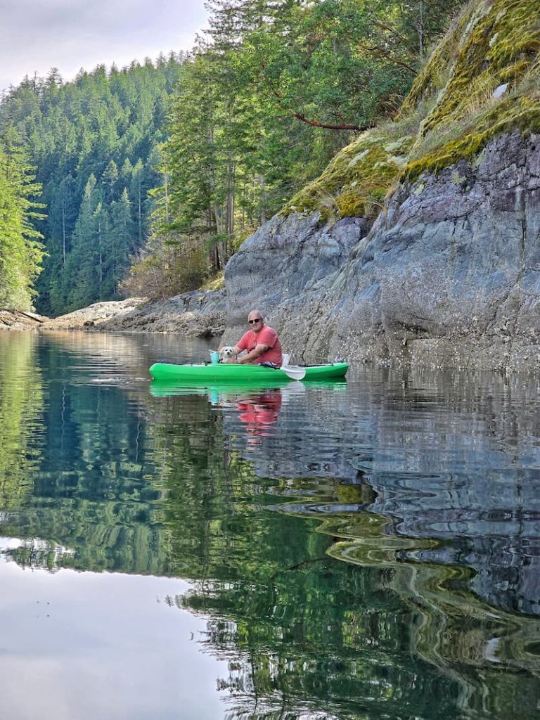 man and cream dog in green kayak on the water