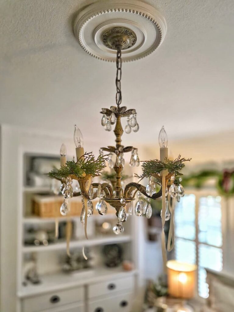 green napkin ring holders placed around the chandelier for Christmas
