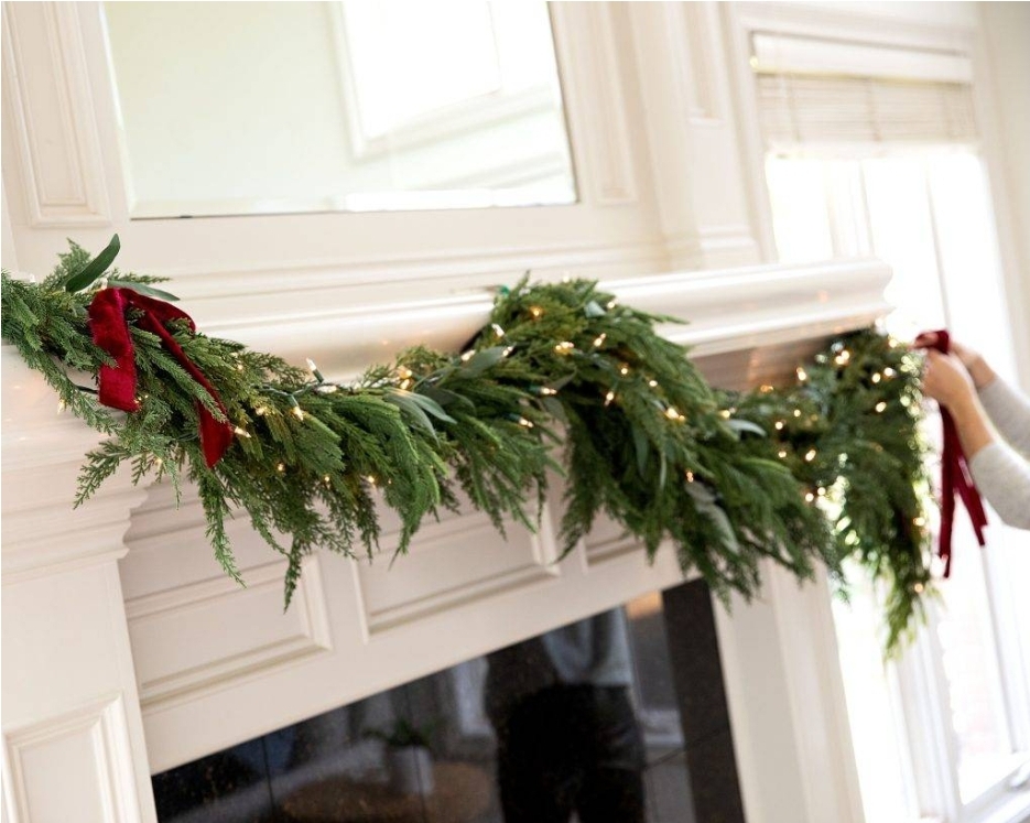 adding red ribbon and lights on the green garland 