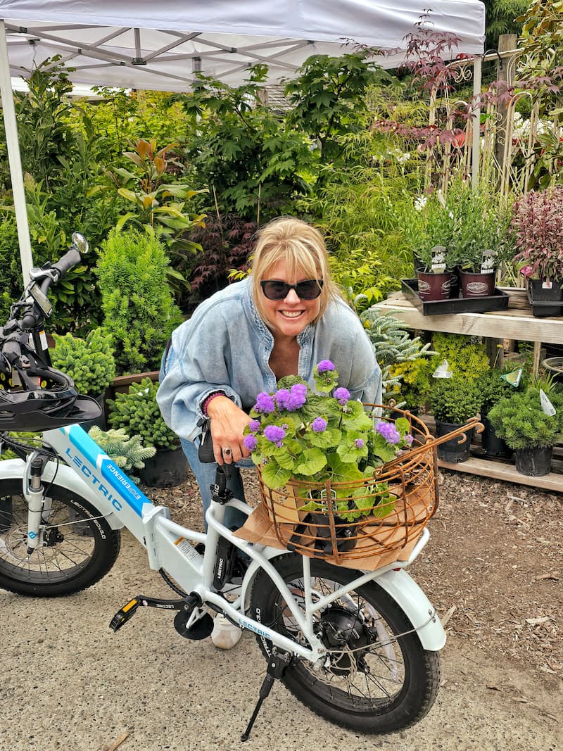 posing in front of nursery with flowers in the bike basket