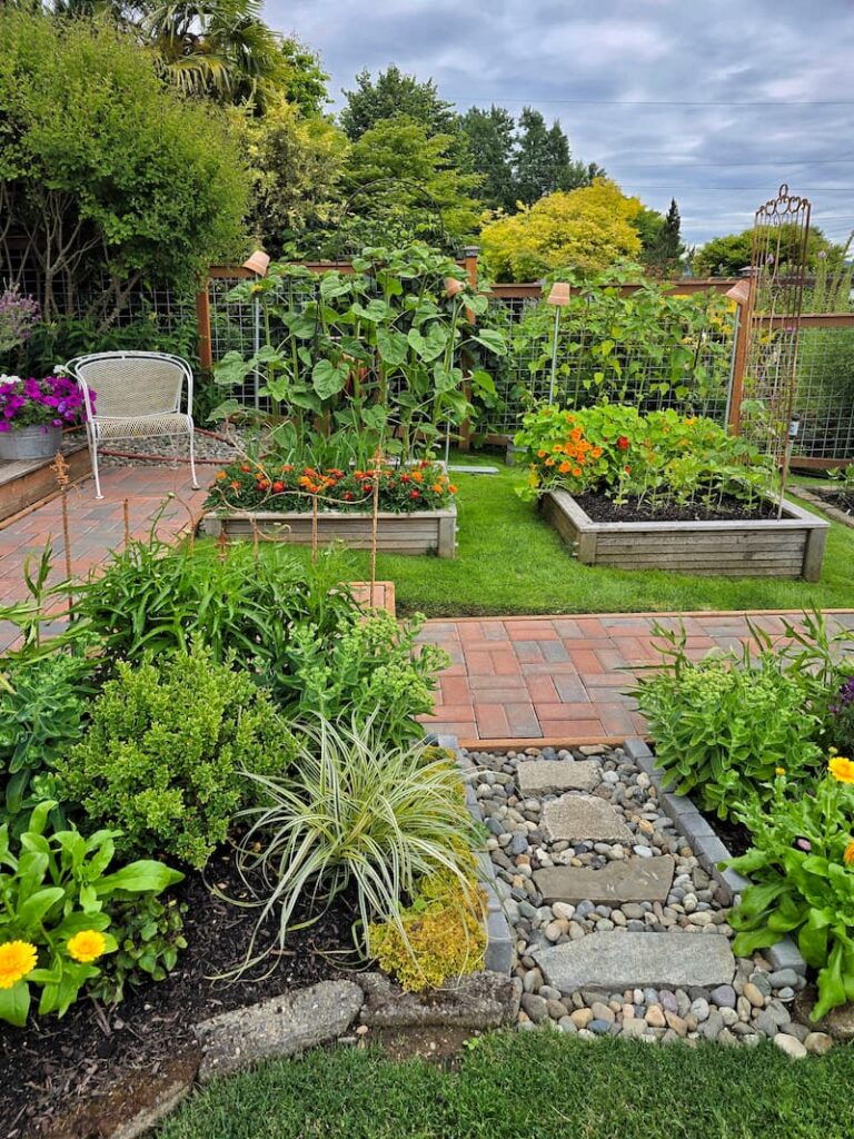 cottage garden with raised beds, a gravel and stone pathway and paver path