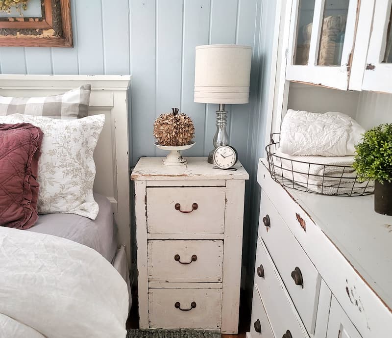 cottage bedroom decorated for fall: cream vintage nightstand with fall decor on it