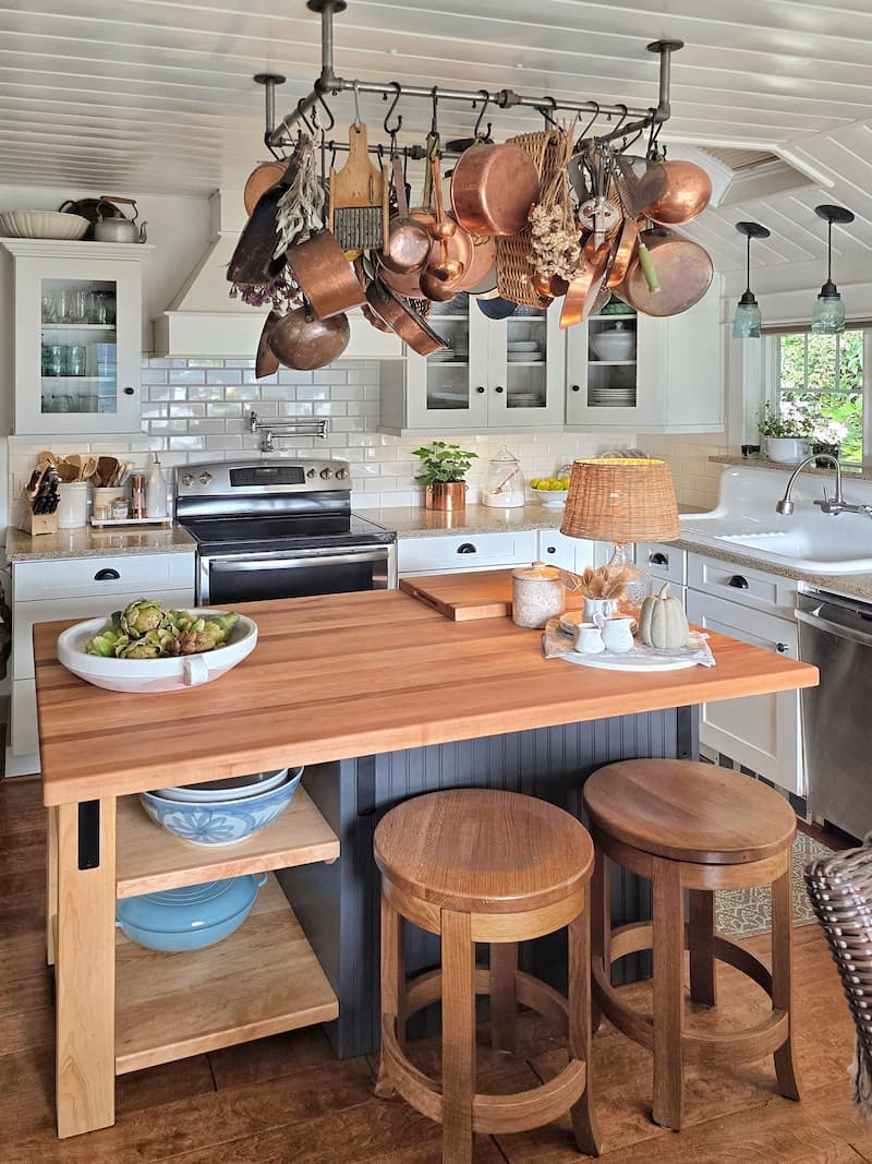cottage kitchen with butcher block top island and copper pans hanging on pot rack