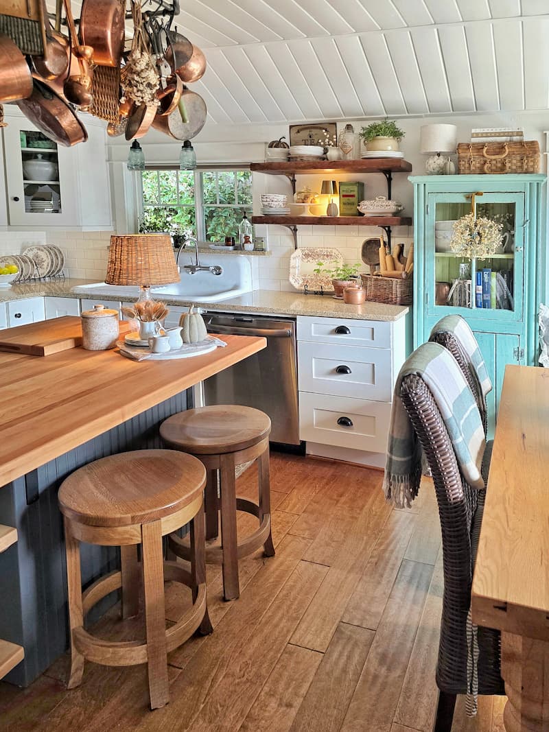 cottage kitchen decorated for fall with open shelving, turquoise cabinet, and butcher block island