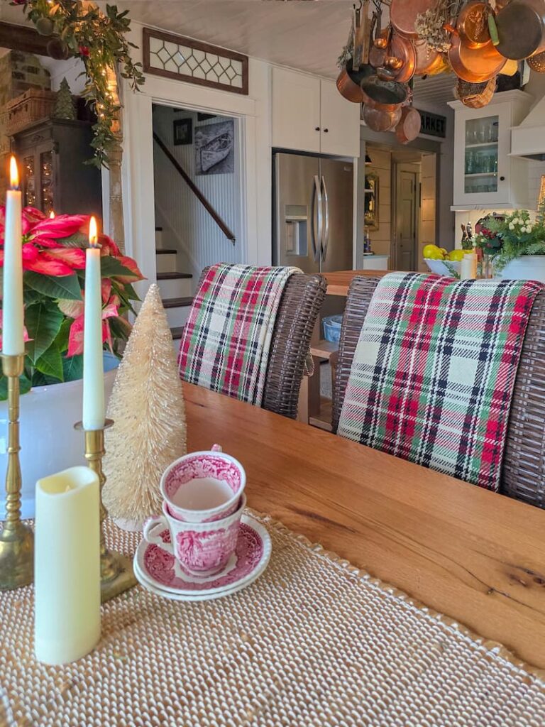 cottage kitchen decorated for Christmas with plaid throws over chairs and red poinsettia