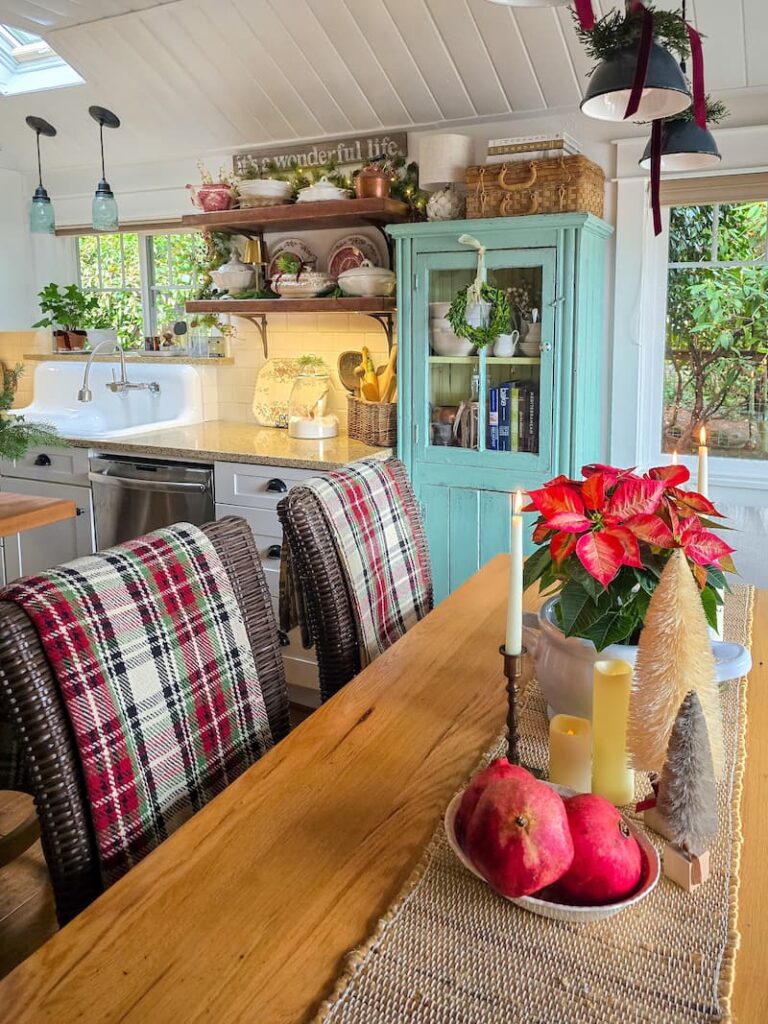 cottage kitchen decorated for Christmas with plaid throws over chairs and red poinsettia