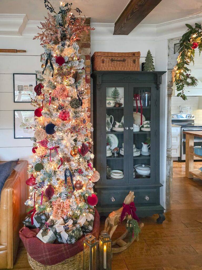 pencil Christmas tree decorated with dark and moody colors and a black glass door cabinet with vintage Spode Christmas collection