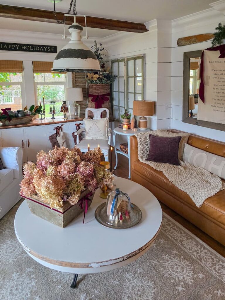 Cottage living room decorated for Christmas with dried hydrangeas on the coffee table and smaller Christmas tree in a basket hanging on the wall