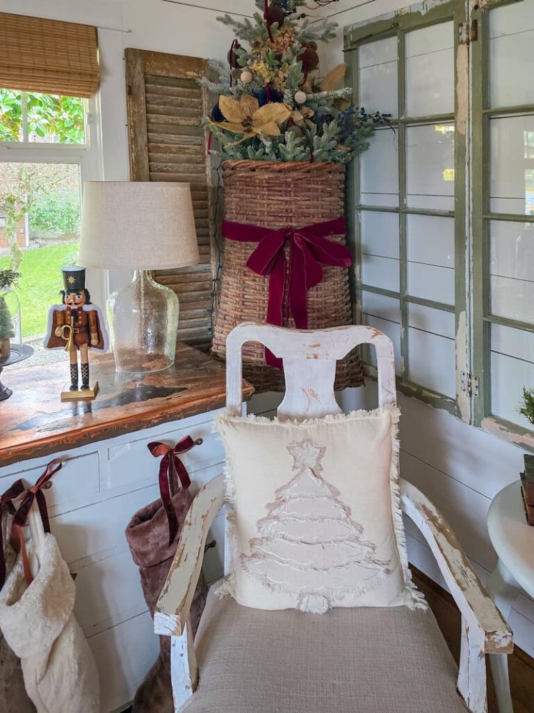cream Christmas tree pillow on chair and Christmas tree hanging on the wall in a basket