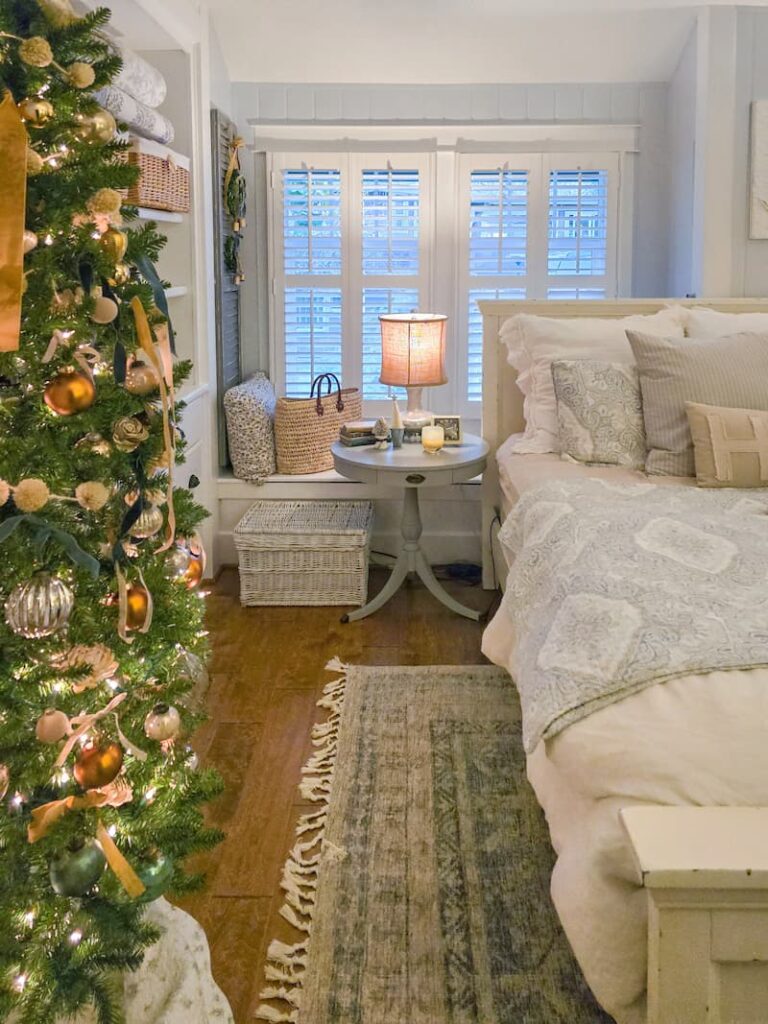 cottage bedroom decorated for Christmas with pale blue and neutral colors and a Christmas tree