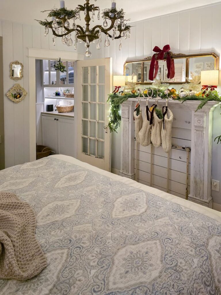 faux fireplace mantel decorated for Christmas with garland, cream knit stockings and a burgundy bow on mirror hanging above