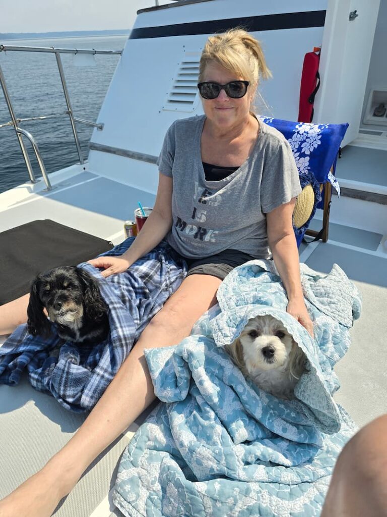 dog mom and 2 dogs on the boat wrapped in blankets
