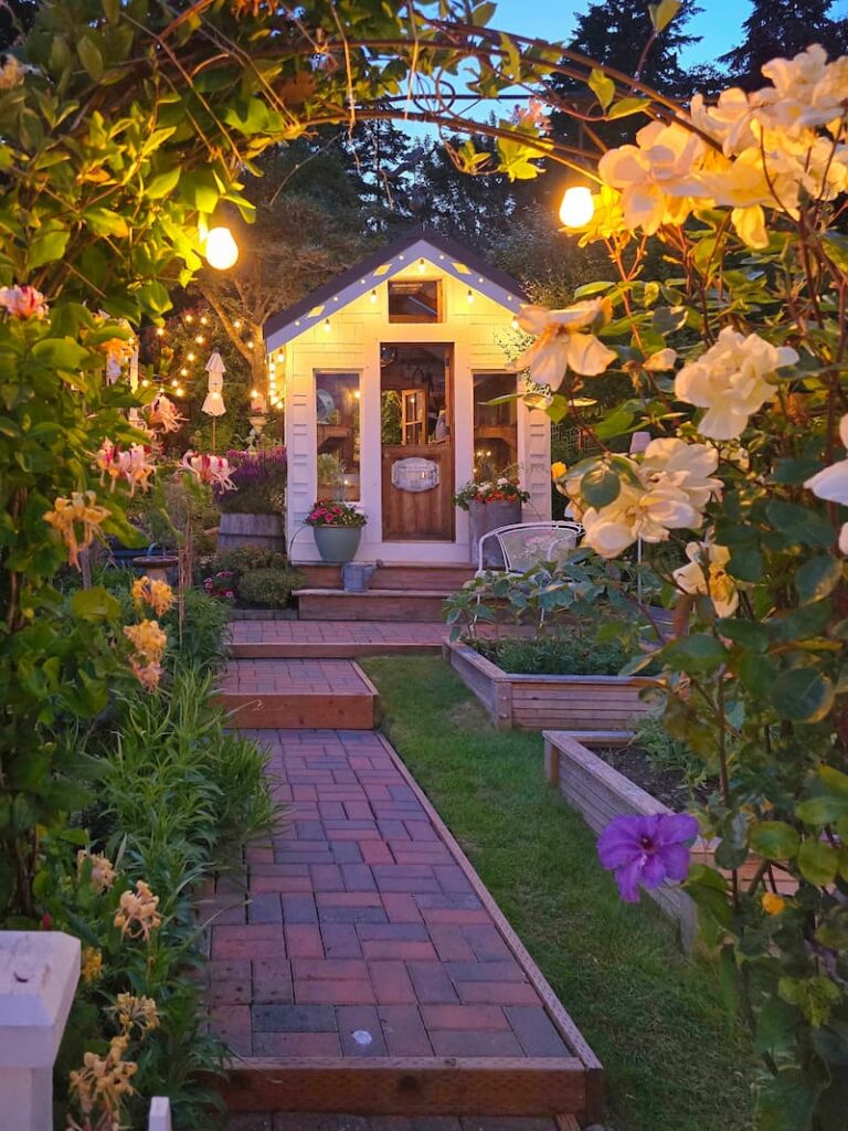 greenhouse and cottage garden evening view with arbor and yellow roses