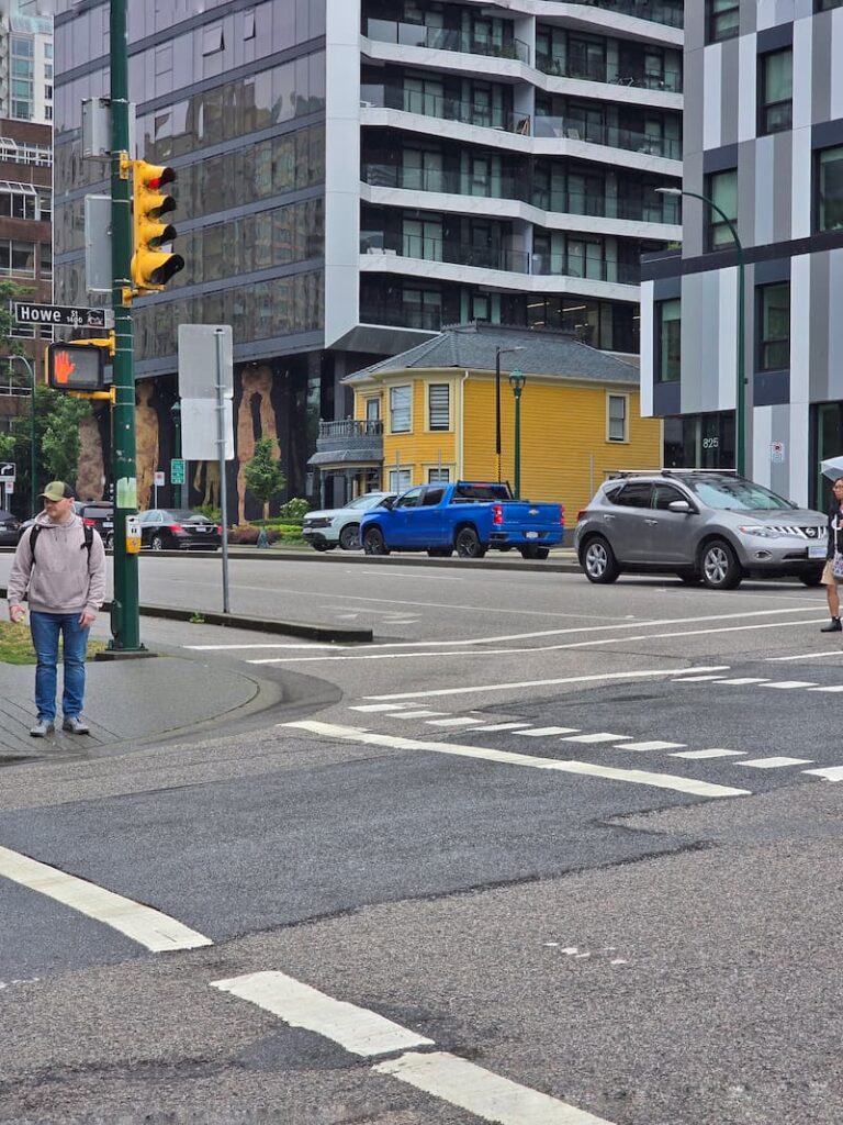 little yellow house completely surrounded by glass towers in Vancouver