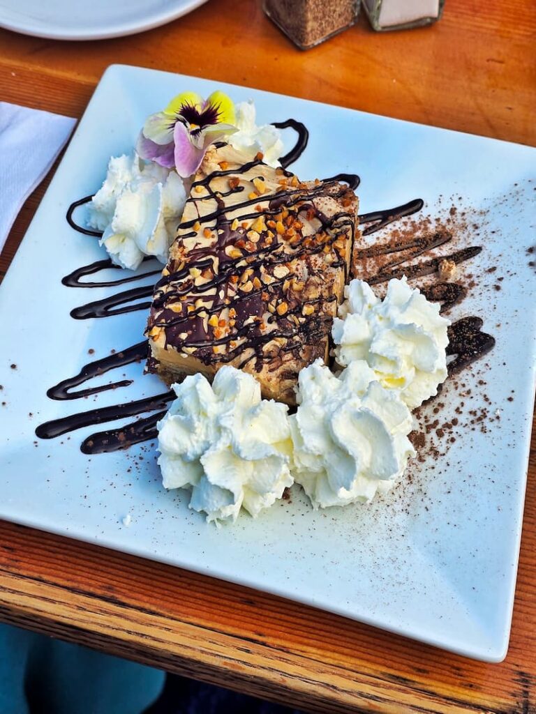 slice of peanut butter cake with whipped cream and pansy