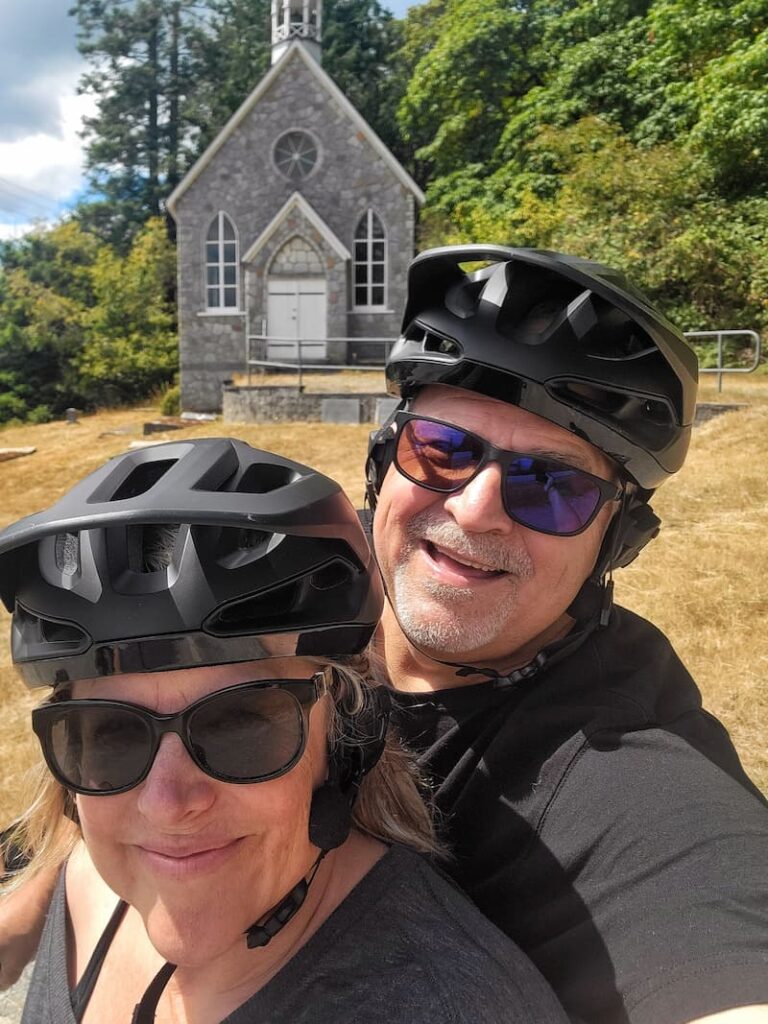 couple with bike helmets on posing in front of stone church