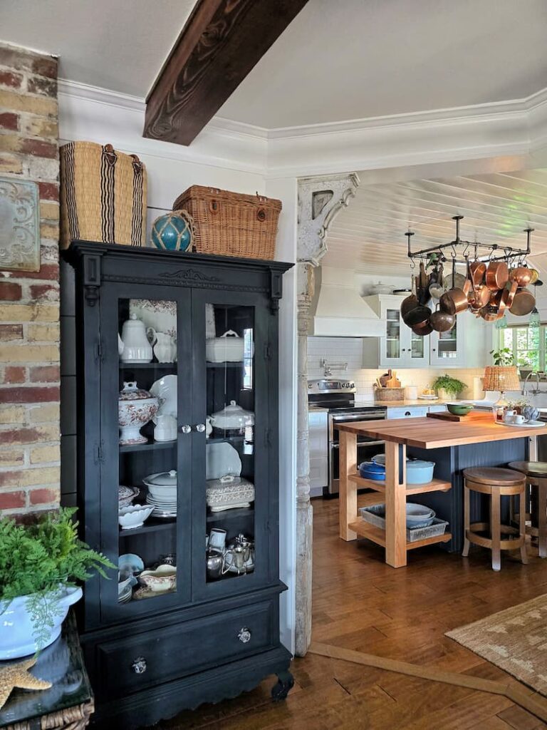 black cabinet with vintage white ironstone collection next to the cottage style kitchen