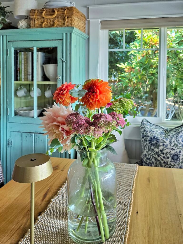 Summer flower centerpiece with zinnias and dahlias on a farmhouse kitchen table