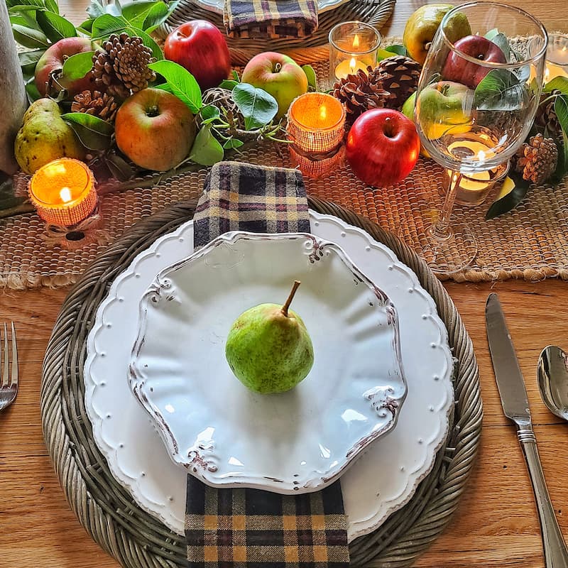 fall table setting with a green pear on a plate and brown plaid napkin
