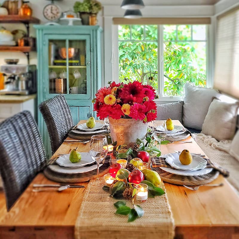 fall table decorated with bucket of bright dahlias and apples and pears for a centerpiece