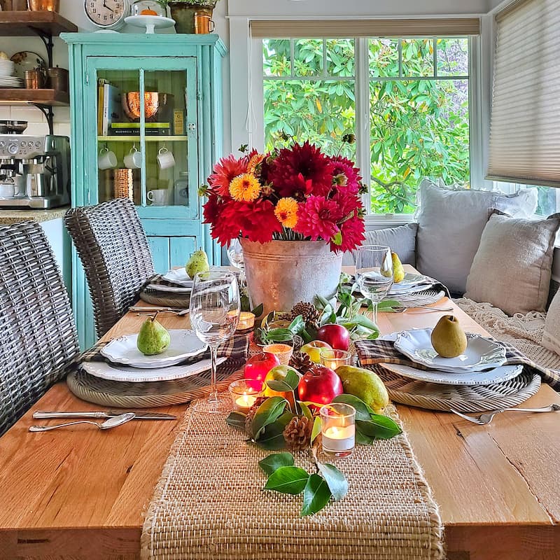 fall tablescape with outdoor elements like apples, pears, and a vintage galvanized bucket of dahlias