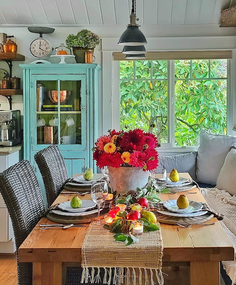 fall tablescape with outdoor elements like apples, pears, and a vintage galvanized bucket of dahlias