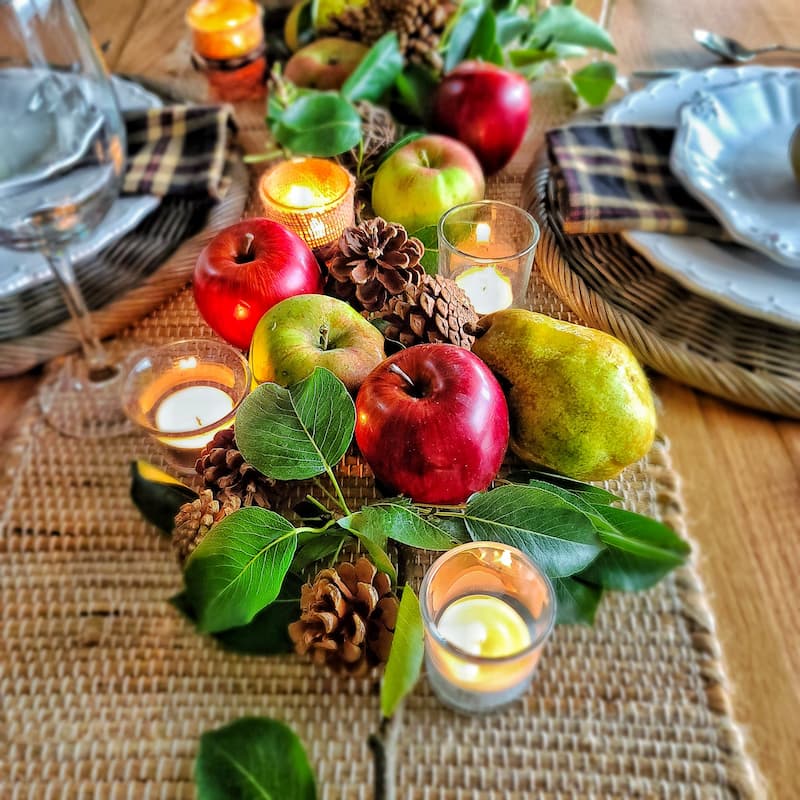apples and pears with pinecones and candles on fall table
