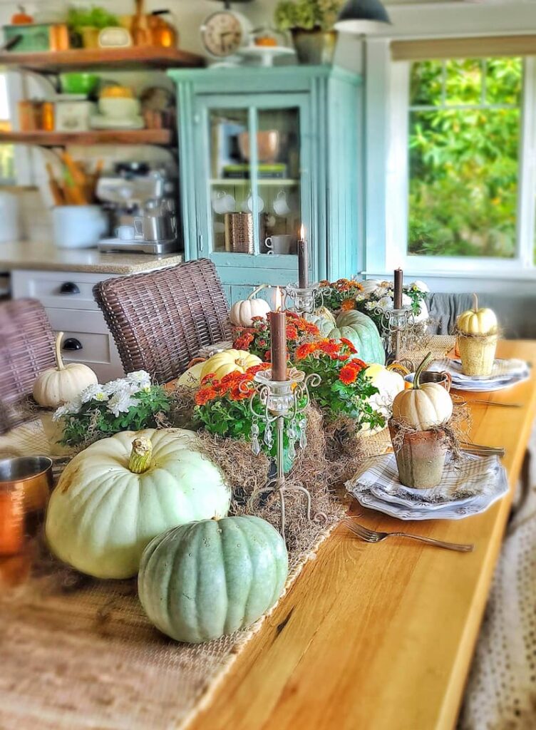 cottage kitchen with teal cabinet and a table decorated for fall with pumpkins and mums
