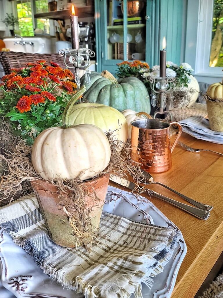 cream and green pumpkin and rust mum centerpiece and mini cream pumpkin on a terra cotta pot with moss