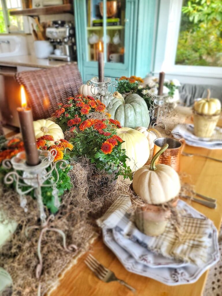 cream and green pumpkins, rust mums, and candlelight make a fall centerpiece