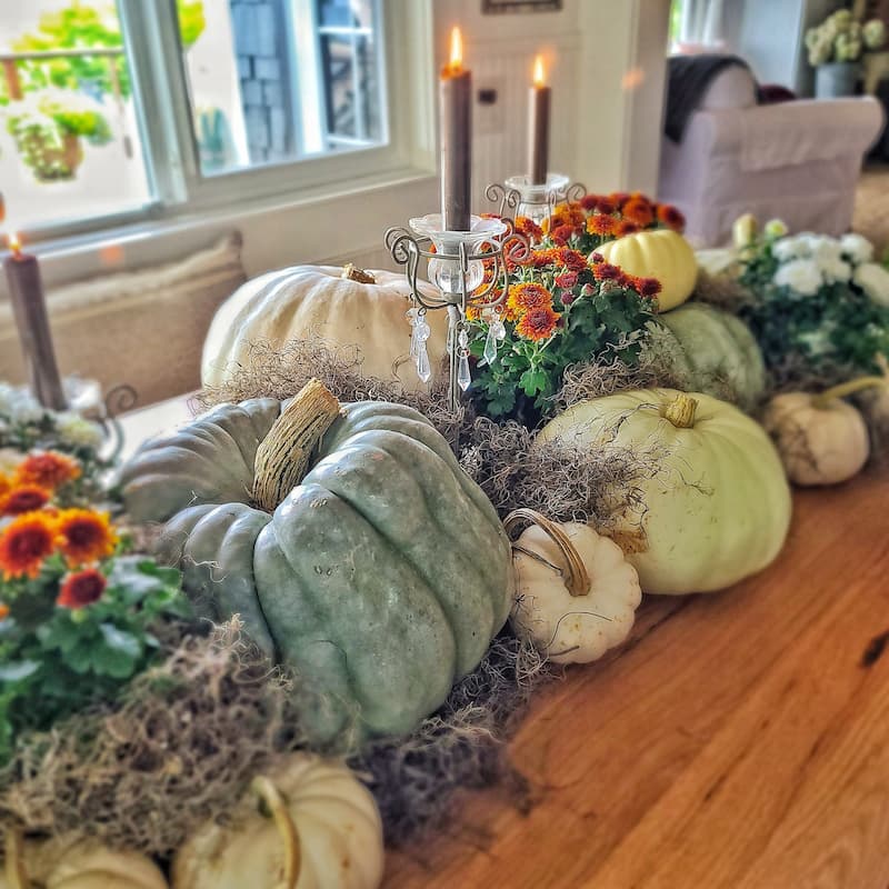 cream and green pumpkins, rust mums, and candlelight make a fall centerpiece
