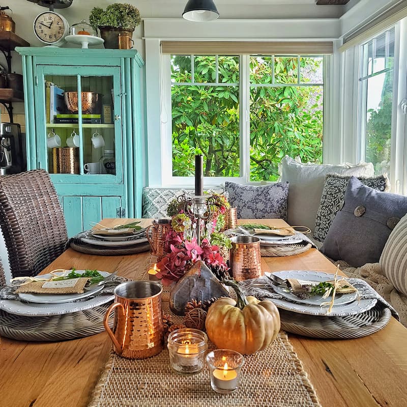 fall tablescape with brown pumpkins, copper mugs, flowers and candlelight