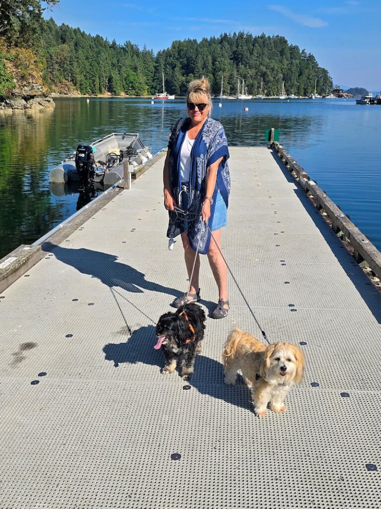 woman holding leashes of black and cream dog on dinghy dock