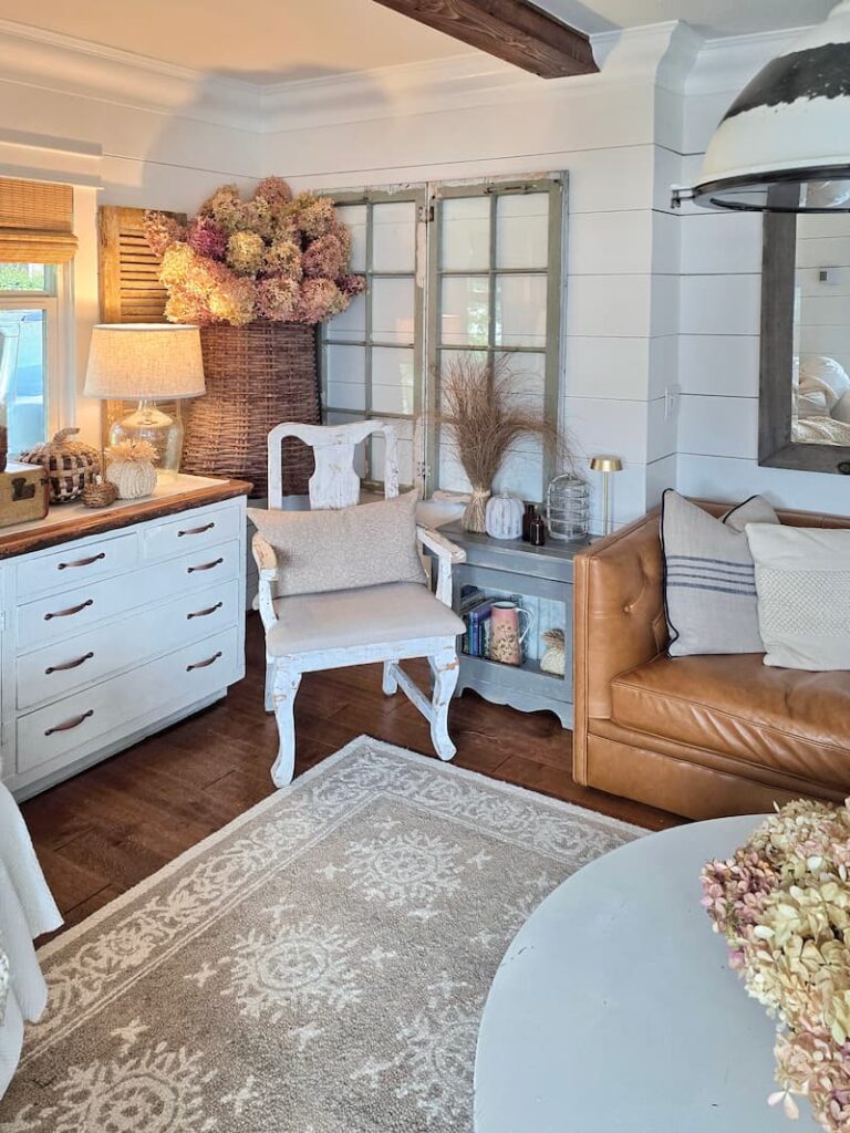 wicker basket hanging on the wall with dried hydrangeas and a cream vintage chair in living room